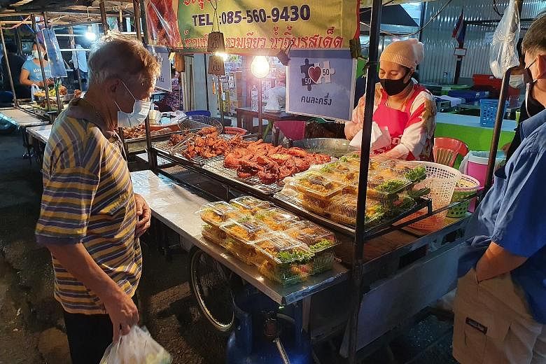 Left: A fried chicken vendor in Nonthaburi province with the Khon La Krueng sign displayed on her food cart. Bottom left: Ms Somsong Samnan, who sells steamed mackerel and eggs at Udom Suk market in Bangkok, steered clear of mobile phones a year ago.