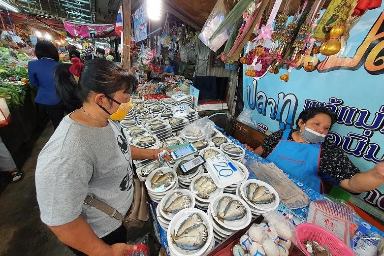 Left: A fried chicken vendor in Nonthaburi province with the Khon La Krueng sign displayed on her food cart. Bottom left: Ms Somsong Samnan, who sells steamed mackerel and eggs at Udom Suk market in Bangkok, steered clear of mobile phones a year ago.
