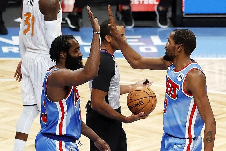 Nets forward Kevin Durant high-fives new teammate James Harden in their 122-115 home win over the Magic on Saturday. Former Rockets guard Harden became the seventh NBA player to score a triple-double (32 points, 12 rebounds, 14 assists) on his debut 