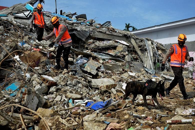 Top: Indonesian police officers searching for victims yesterday among the ruins of a hospital building, following an earthquake in Mamuju, West Sulawesi province. Above: Indonesian President Joko Widodo in South Kalimantan yesterday. He inspected dam