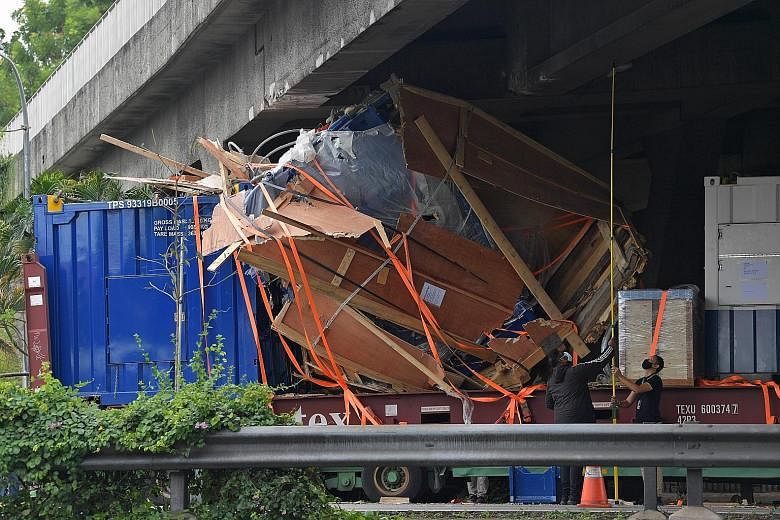 Goods in a trailer lorry wedged beneath the flyover on Ayer Rajah Expressway, just after the Clementi Avenue 2 exit, yesterday. The incident blocked all but one lane on the expressway towards the Marina Coastal Expressway, causing congestion for hour