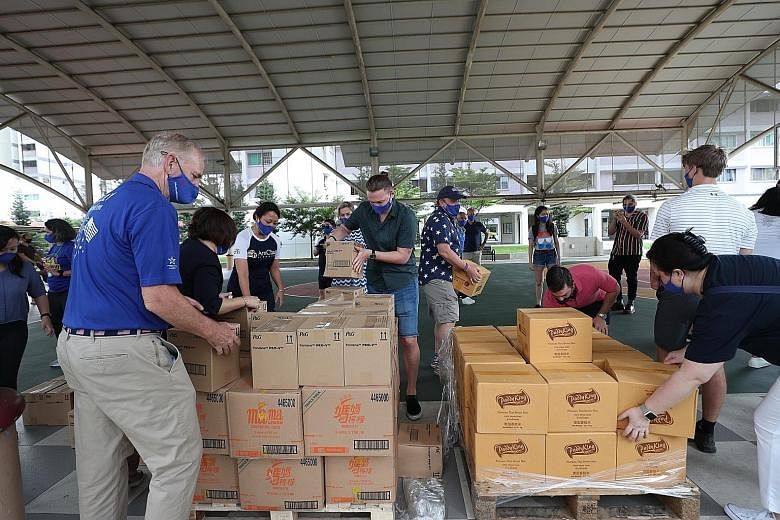 American Association of Singapore president Blair Hall (left) and American Chamber of Commerce in Singapore chief executive Lei Hsien-Hsien (right) with a group of Americans distributing care packs of food and daily necessities to needy families at a
