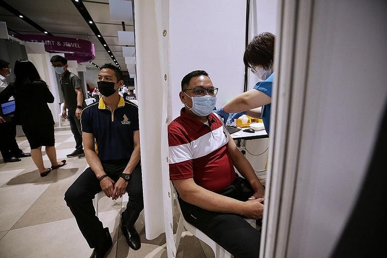 The vaccination centre's lead physician Tan Joo Peng said there is scope to ramp up capacity even further. Above: Front-line workers from the aviation industry receiving the Covid-19 vaccine at Changi Airport Terminal 4 yesterday. Below: Workers regi