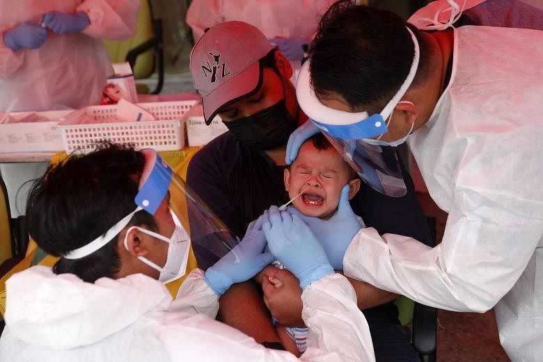 Medical personnel taking a swab sample for a Covid-19 test from an infant in Shah Alam, outside Kuala Lumpur, yesterday. Prime Minister Muhyiddin Yassin announced a new aid package totalling RM15 billion (S$4.9 billion), which will help front-liners 