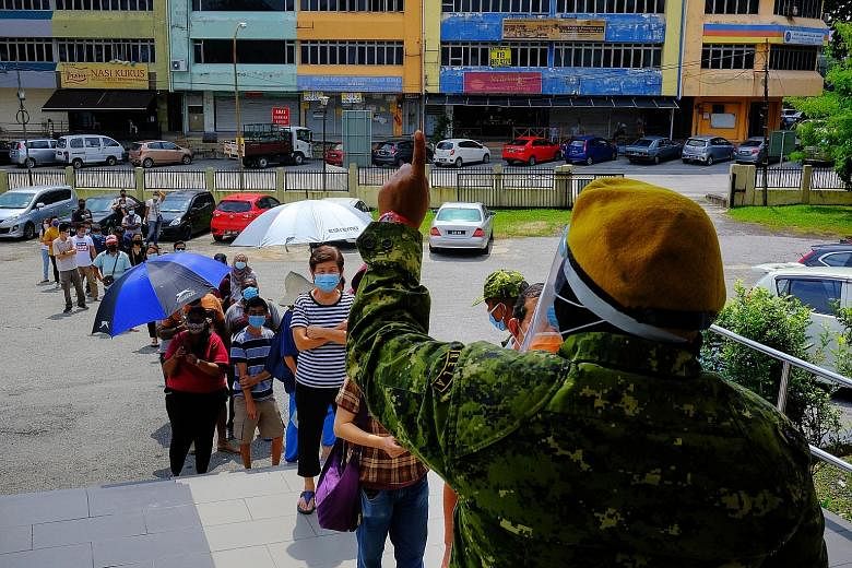 People waiting outside a temporary Covid-19 testing centre at the Subang Jaya City Council public hall in Petaling Jaya, Malaysia, yesterday. PHOTO: BLOOMBERG