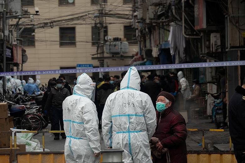Workers clad in protective suits at an area that had been cordoned off near Renji Hospital in Shanghai yesterday, following a suspected case of coronavirus infection at the hospital. A total of 144 new Covid-19 cases were reported in China on Wednesd