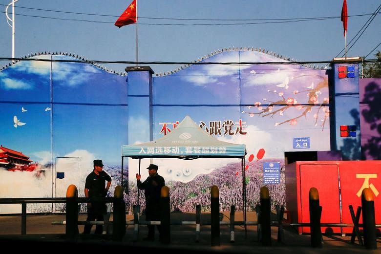 Security guards at the gates of what is officially known as a vocational skills education centre in Xinjiang Uighur Autonomous Region, in a file photo taken in September 2018. The entrance is adorned with Chinese flags and features giant prints of Ch
