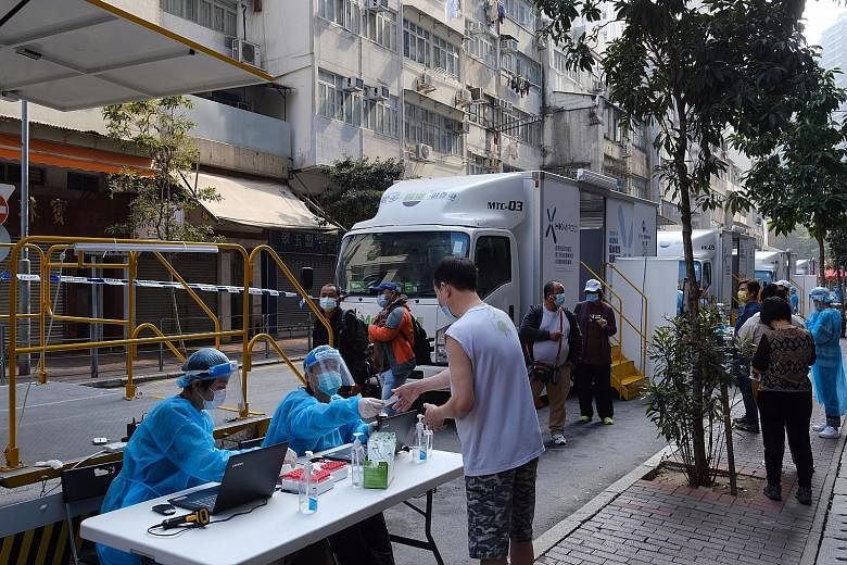 Left: Health workers assisting residents at mobile testing centres for Covid-19 in the Yau Ma Tei area of Yau Tsim Mong in Hong Kong yesterday. The lockdown is expected to begin this weekend, and involve 150 residential buildings in Yau Tsim Mong, ac