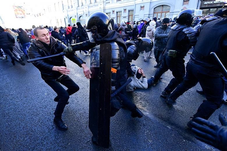 Police in full riot gear beating protesters with batons yesterday in Vladivostok, where demonstrators had congregated in the city centre, chanting "Putin is a thief" and "Freedom to Navalny". Above: People in Omsk, Siberia, heeding Kremlin critic Ale