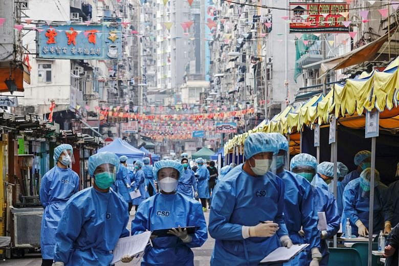 Health workers in protective gear inside a locked-down portion of the Jordan residential area in Hong Kong yesterday. More than 3,000 government staff were deployed to set up 51 testing stations and to go door to door to get people to go for the Covi