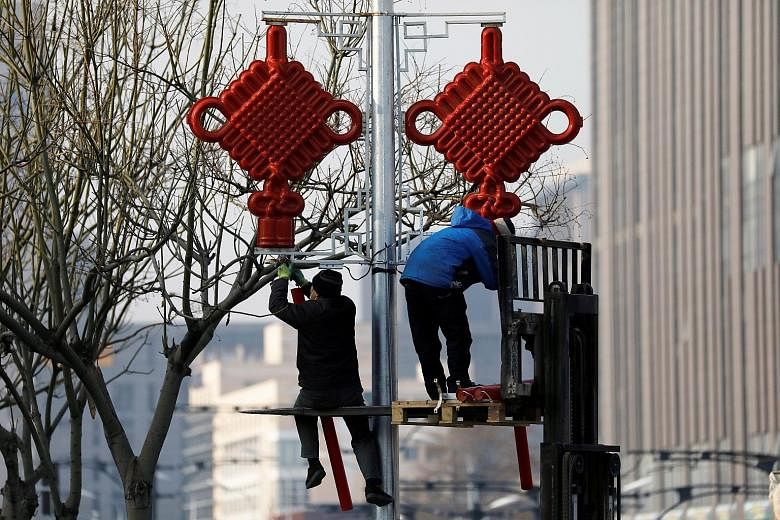Workers putting up street lights in the shape of a Chinese knot in Beijing last week, ahead of the Chinese New Year holiday. After a spike in infections that began late last month - with many local transmissions in Hebei, Heilongjiang and even the Ch