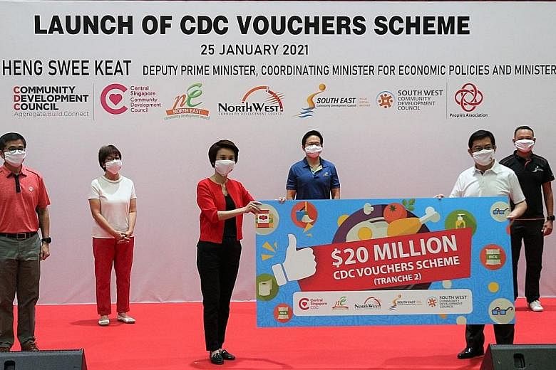 Deputy Prime Minister Heng Swee Keat and South West District Mayor Low Yen Ling holding a placard at the launch of the second tranche of vouchers under the Community Development Council Vouchers Scheme at Bedok Community Centre yesterday. With them a