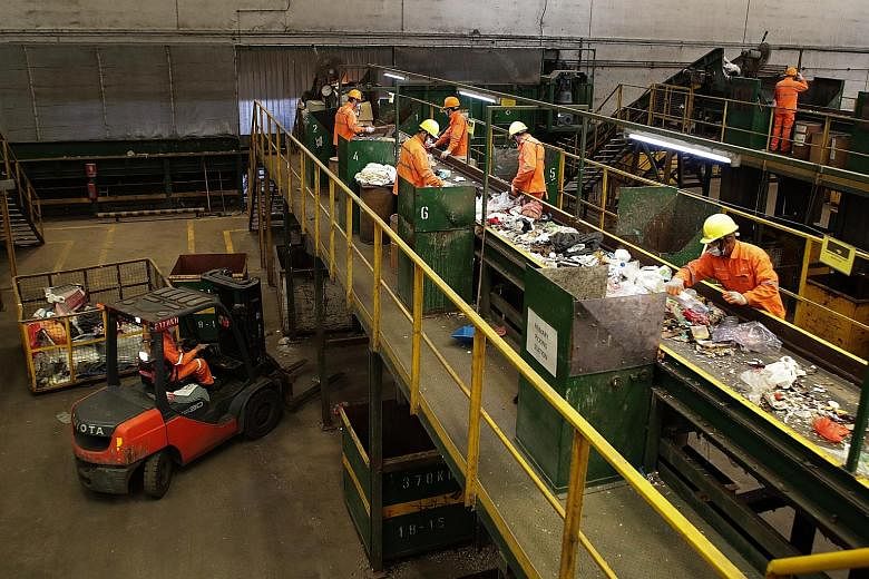 Workers at SembWaste sorting through waste materials for recycling at the facility in Tuas yesterday. The new Tripartite Cluster for Waste Management, comprising representatives from the labour movement, employers, industry associations, service buye