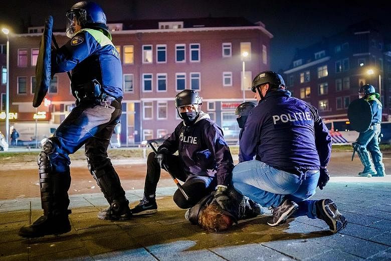 Dutch police arresting a man during clashes with a group of young people in Rotterdam on Monday. Protests have broken out in the Netherlands following the introduction of a Covid-19 curfew over the weekend. 