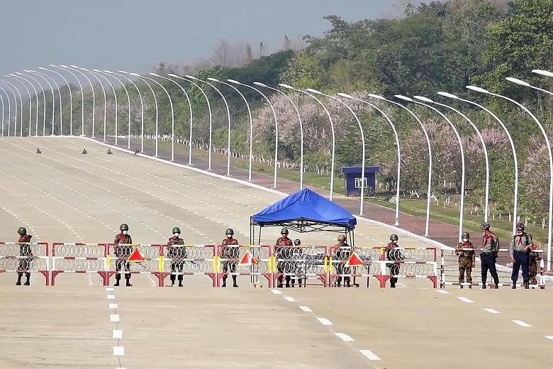 Soldiers standing guard on a road leading to Myanmar's Parliament building in Naypyitaw yesterday, after the military detained the country's civilian leader Aung San Suu Kyi and President Win Myint. Above: Myanmar soldiers seen inside Yangon City Hal