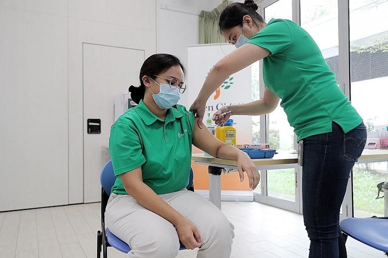 Above: Land transport workers going through a registration process before receiving their Covid-19 shots on Jan 25 at the vaccination centre set up at the former Hong Kah Secondary School. Left: Healthcare assistant Nurzawani Mohamad Kamal, 24, from 
