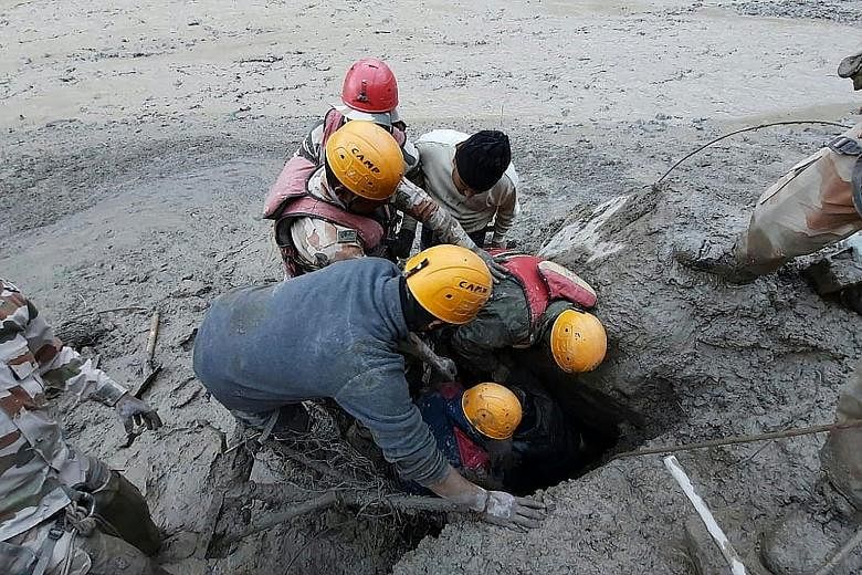 Above: Workers clearing a blocked tunnel in Tapovan village in Uttarakhand yesterday. Left: Members of the Indo-Tibetan Border Police in a rescue operation in Reni village in Uttarakhand on Sunday. PHOTOS: AGENCE FRANCE-PRESSE