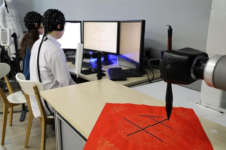 A robot arm, controlled by researchers' minds, writing the Chinese character for ox at the Academy of Medical Engineering and Translational Medicine under Tianjin University in China.