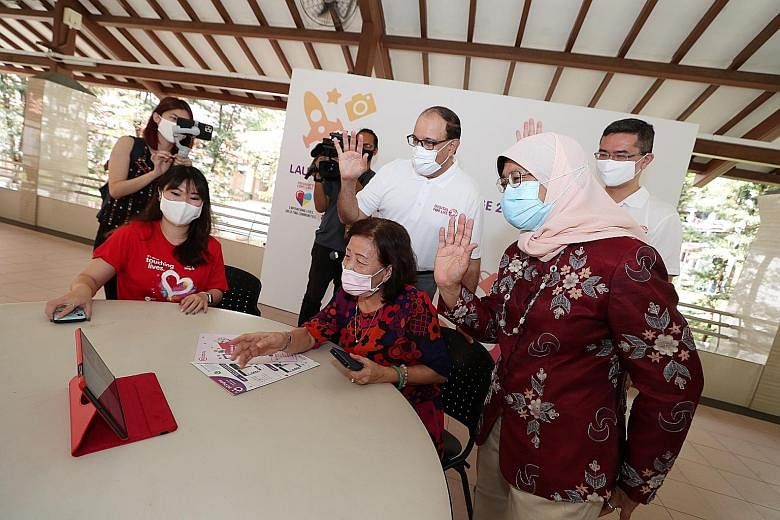 President Halimah Yacob and Minister for Communications and Information S. Iswaran (centre) with Madam Patsy Low, 69, as she makes a video call to her sister, guided by Singtel volunteer Elina Ang (left), at NTUC Health's Senior Activity Centre in Ta