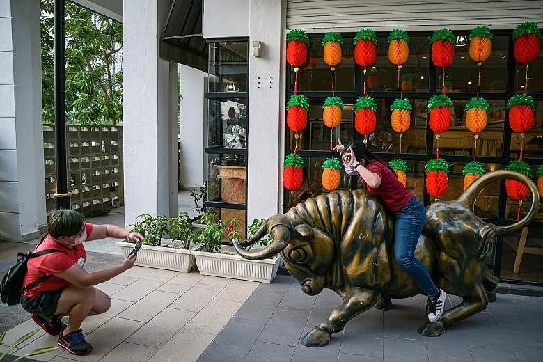 A woman posing for pictures on a bull statue in Cyberjaya yesterday ahead of Chinese New Year on Friday. PHOTO: AGENCE FRANCE-PRESSE