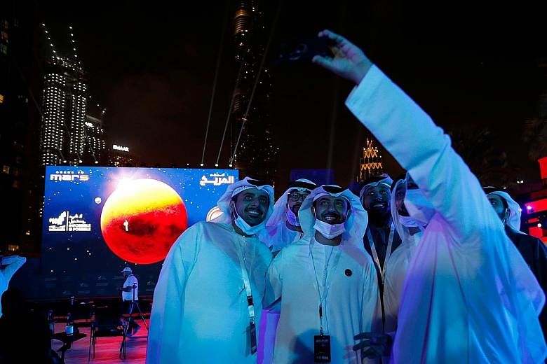 People watching an outdoor big screen that showed footage of the United Arab Emirates' Hope Probe entering Mars orbit on Tuesday at Burj Plaza, in front of the world's tallest building of Burj Khalifa, in Dubai.