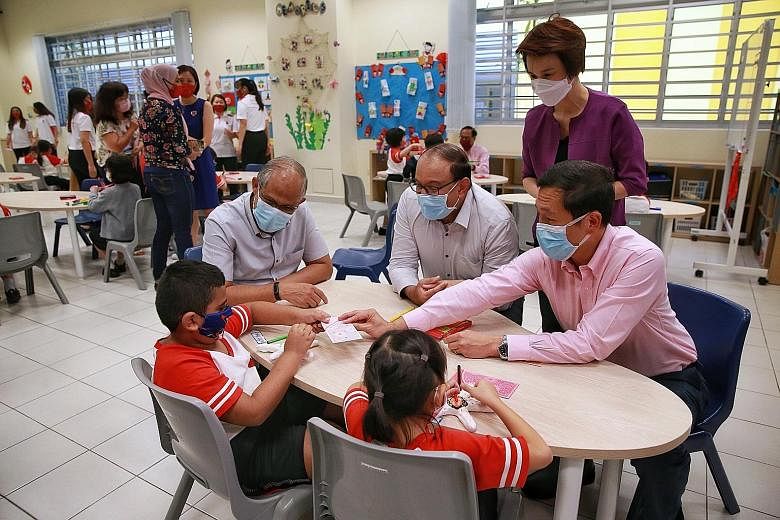 Interacting with Primary 1 pupils Mohd Aazim Idris Raja Mohd and Leann Ng at the Big Heart Student Care centre in Zhangde Primary School yesterday were (from left) Minister for Social and Family Development Masagos Zulkifli, Minister for Communicatio