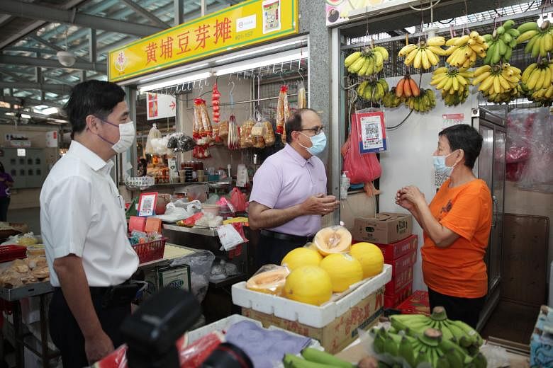 Madam Lim Meng Kee, a stallholder at Whampoa Drive Food Centre and Market, with Minister for Communications and Information S. Iswaran and Jalan Besar GRC MP Heng Chee How, who is also Senior Minister of State for Defence, yesterday. Madam Lim, who r
