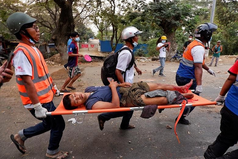 An injured man being carried away by rescue workers after a protest in Mandalay yesterday against the Feb 1 military coup. The police had opened fire to disperse protesters at Yadanarbon shipyard.