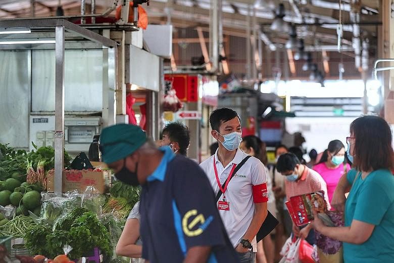 A safe distancing enforcement officer at work at a wet market. The Ministry of Sustainability and the Environment says agencies will continue to step up enforcement inspection of food and beverage premises, shopping malls, parks and beaches to curb a