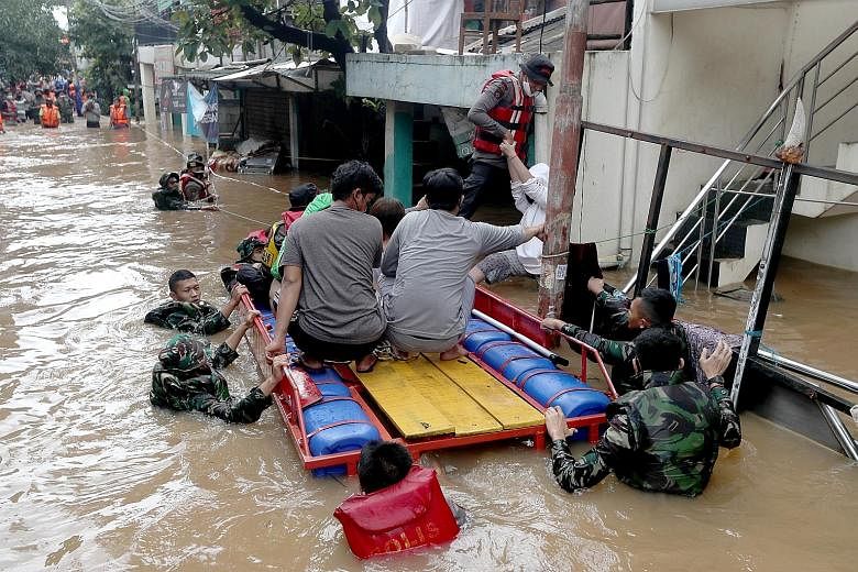 Indonesian military and police officers helping flood victims get into a boat while rescuing residents in Jakarta yesterday.