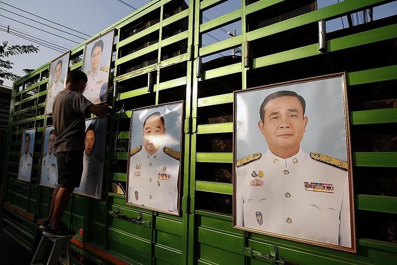 Photographs of Thai Prime Minister Prayut Chan-o-cha (far right) and members of his Cabinet being put up at an anti-government rally outside Parliament in Bangkok yesterday. The government's victory comes as pro-democracy protests returned after a lu