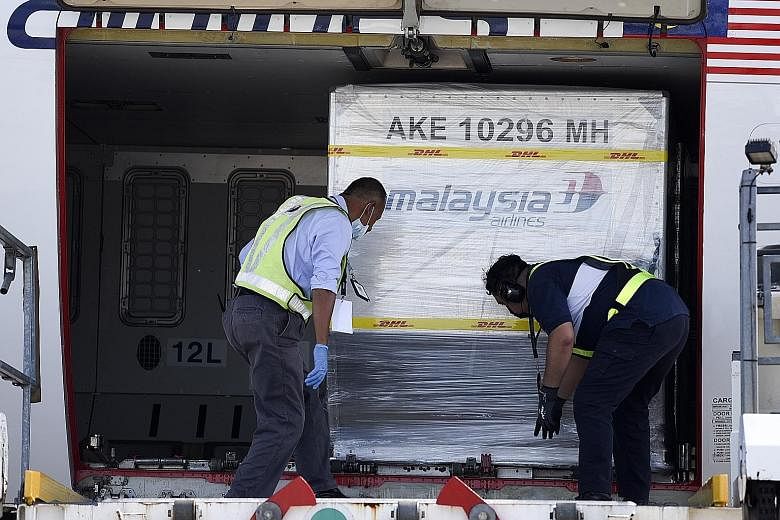 Containers carrying Pfizer-BioNTech Covid-19 vaccines being unloaded from a Malaysia Airlines plane at Kuala Lumpur International Airport yesterday, in a handout photo made available by Malaysia's Department of Information. Malaysian Prime Minister M