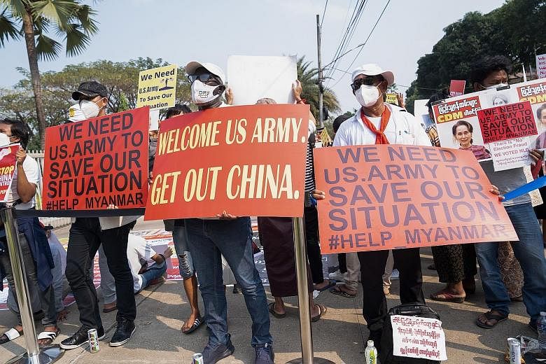 Protesters outside a foreign embassy in Yangon on Thursday holding signs urging the US to intervene in Myanmar. They hope global pressure will tip the scales in their favour. PHOTO: KYAW ZA