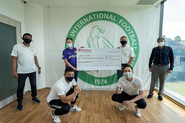 Geylang International committee member Carlo Nohra (far right) watches on while South East District Mayor Fahmi Aliman receives a cheque for $20,000 from Geylang chairman Thomas Gay (in blue) yesterday. The money will benefit the district's underpriv