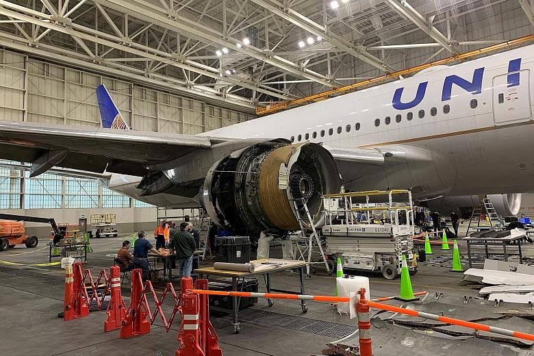 United Airlines (UA) Flight 328, a Boeing 777-200, with its damaged engine in a hangar at Denver International Airport on Monday. Part of the plane's engine caught fire and broke off during a flight at the weekend, prompting UA and other airlines to 