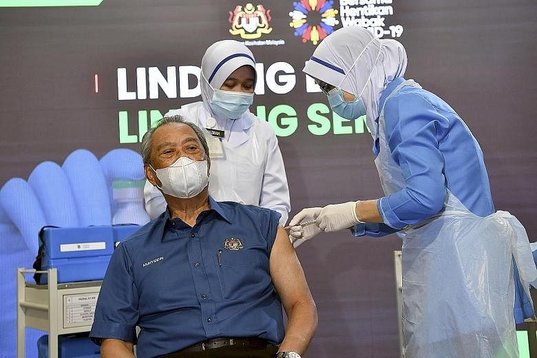 Malaysian Prime Minister Muhyiddin Yassin receiving his first dose of the Pfizer-BioNTech Covid-19 vaccine at a public clinic in Putrajaya yesterday. The event was broadcast to the public with the aim of showing Malaysians the steps involved in the v
