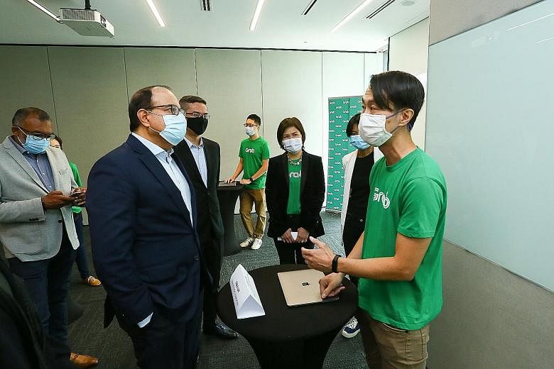 Minister for Communications and Information S. Iswaran (second from left) speaking yesterday to Mr Jesse Lim, 47, who heads five product teams at Grab, including customer support experience.