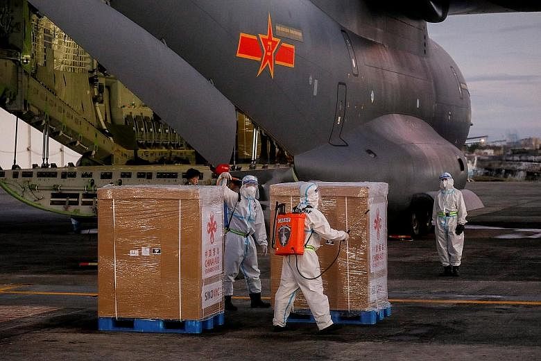 Workers in protective suits disinfecting boxes of Sinovac's Covid-19 vaccine after unloading them from a Chinese military aircraft at Villamor Airbase in Pasay, Metro Manila, yesterday. The first doses would be given at six hospitals today, with the 