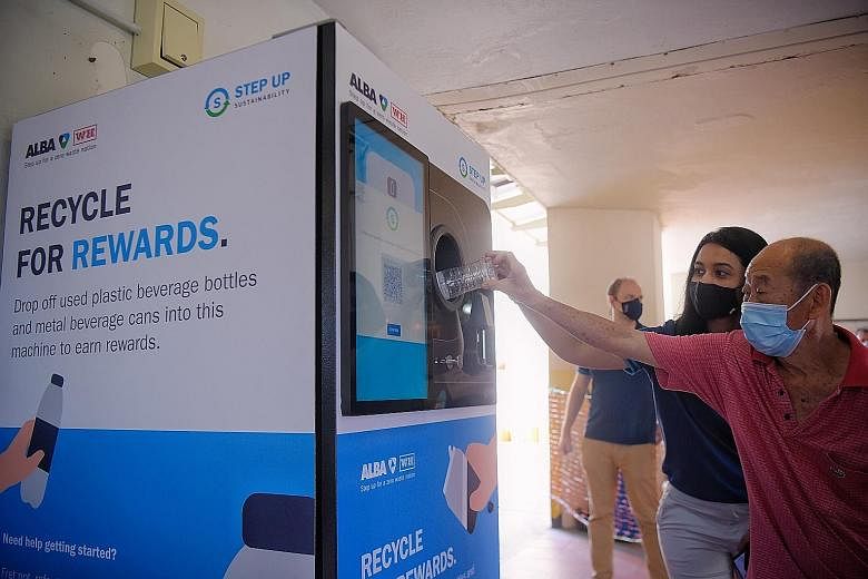 Alba W&H Smart City assistant sustainability manager Sandra Sajan helping a Jurong resident use the new reverse vending machine at Yuhua Food Centre yesterday. The food centre is one of five locations where the machines are being installed. All five 