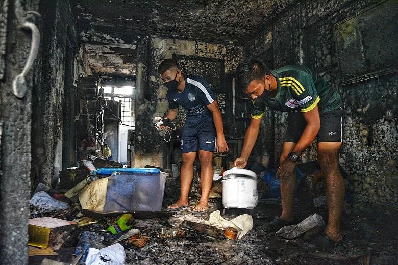 Brothers Muhammad Huzaimi Zuraimi (far left), 22, and Muhammad Haiqal Zuraimi, 23, both residents of the affected flat in Jalan Tenteram, salvaging their belongings yesterday afternoon. ST PHOTO: DESMOND WEE