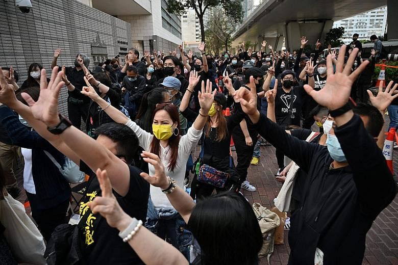 Pro-democracy supporters (above) showing hand signs outside the West Kowloon court in Hong Kong yesterday, ahead of the court appearances of dozens of activists charged with conspiracy to commit subversion under Beijing's new national security law. P