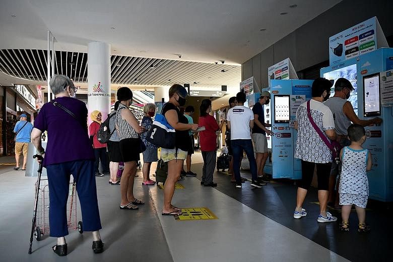 Residents collecting their free masks yesterday from mask vending machines at Our Tampines Hub, in Temasek Foundation's fourth mask distribution exercise. Yesterday was the first day of the distribution, which will end on March 14. The mask, called M