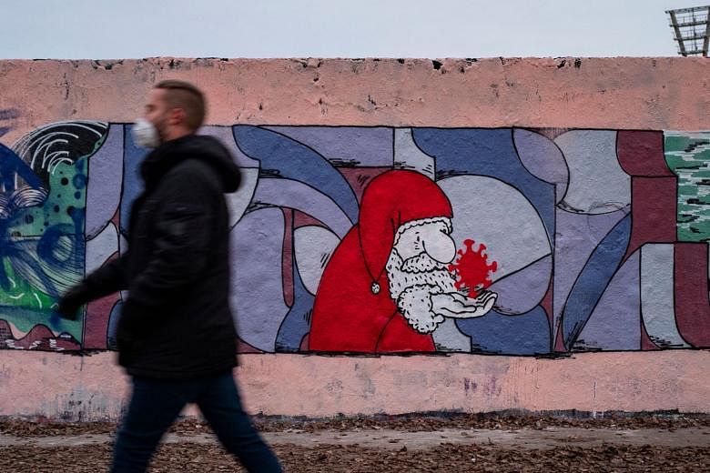 A man wearing a face mask walking past a mural painting featuring a likeness of Santa Claus holding a Sars-CoV-2 molecule, in Berlin last year. Scientists have been arguing for about a century over whether viruses are alive, ever since the pathogens 