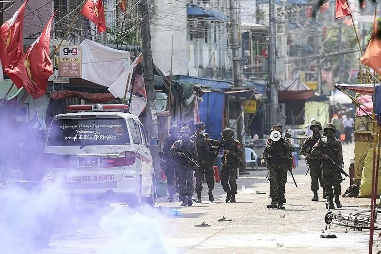DANGER: Protesters facing off against the police during a demonstration in Mandalay yesterday against Myanmar's military coup. PHOTO: AGENCE FRANCE-PRESSE TAKING COVER: Protesters in Yangon hiding behind makeshift shields (left) during a demonstratio