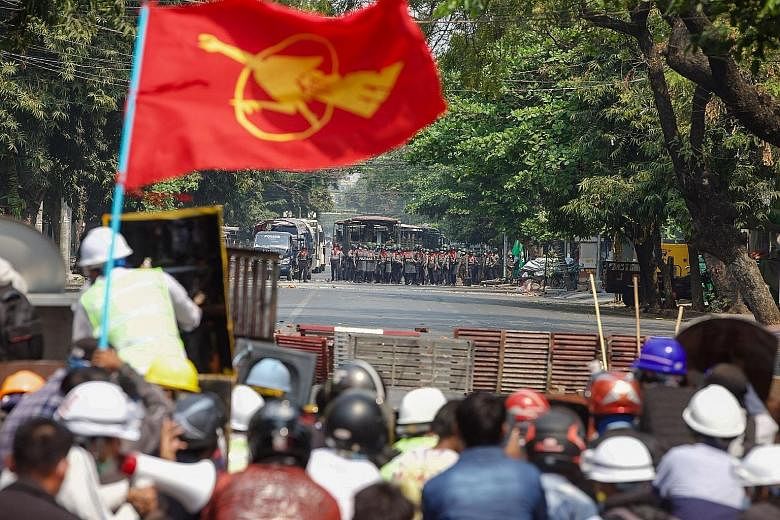 DANGER: Protesters facing off against the police during a demonstration in Mandalay yesterday against Myanmar's military coup. PHOTO: AGENCE FRANCE-PRESSE TAKING COVER: Protesters in Yangon hiding behind makeshift shields (left) during a demonstratio