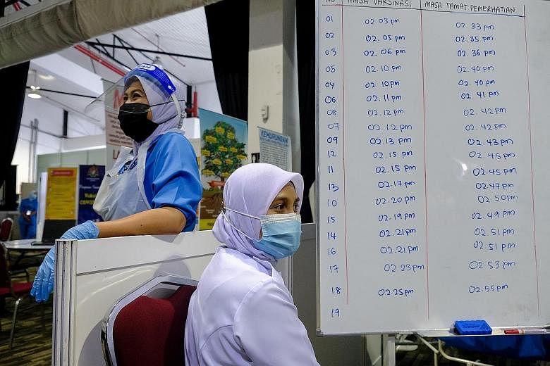 Healthcare workers next to a board listing the times of administering the Covid-19 vaccine to front-liners at a vaccination centre in Selangor on Thursday. Malaysia launched its mass vaccination programme on Feb 24.