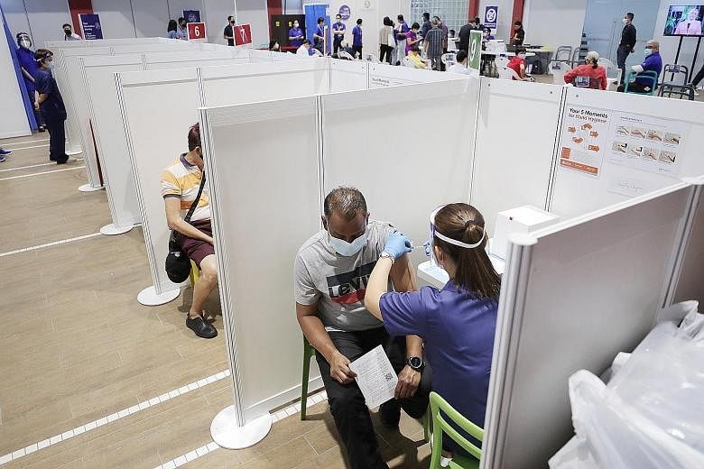 Above: A man getting his Covid-19 jab at the vaccination centre in Jalan Besar Community Club last month. ST PHOTO: GAVIN FOO Left: Prime Minister Lee Hsien Loong speaking to BBC's Asia business correspondent Karishma Vaswani in an interview broadcas