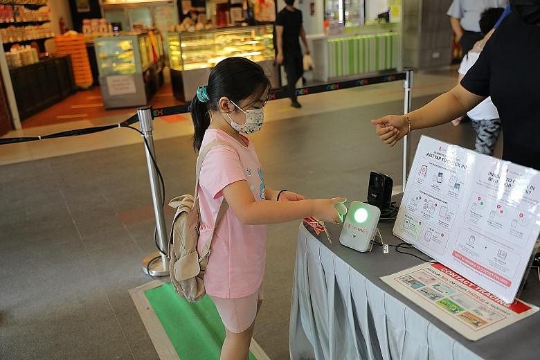 A visitor checking in at Nex mall yesterday by placing a TraceTogether token close to the SafeEntry Gateway Box. The box works by exchanging Bluetooth signals with the TraceTogether app on a phone or token within a 25cm range. ST PHOTO: ONG WEE JIN