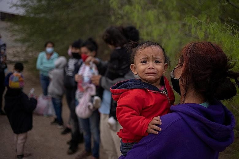 An 18-month-old girl from Honduras crying while being carried by her mother as they and other migrants wait to be transported by the US Border Patrol after crossing the Rio Grande on a raft to the US state of Texas from Mexico on Monday. About 100,00
