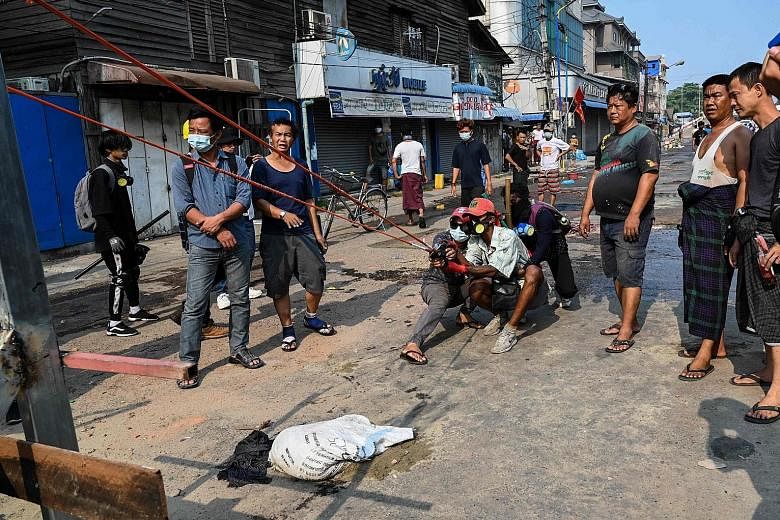 Protesters testing a large slingshot weapon in Yangon yesterday, as security forces continued a crackdown on demonstrations against the military coup. Social media footage showed protesters confronting security forces over a sandbag barricade in the 